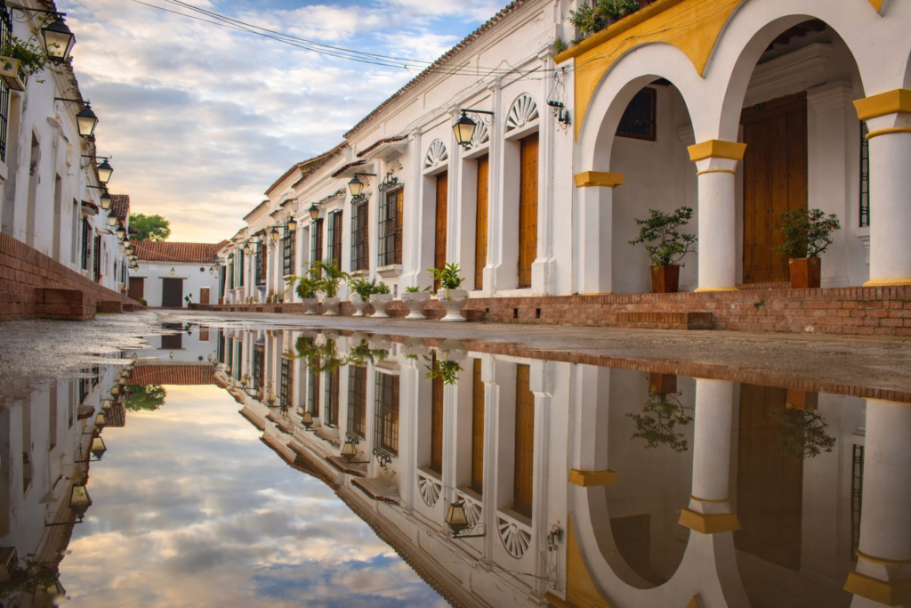 Rue coloniale de Mompox après la pluie, avec maisons blanches à arcades et reflets sur le sol, dans le centre historique classé UNESCO en Colombie